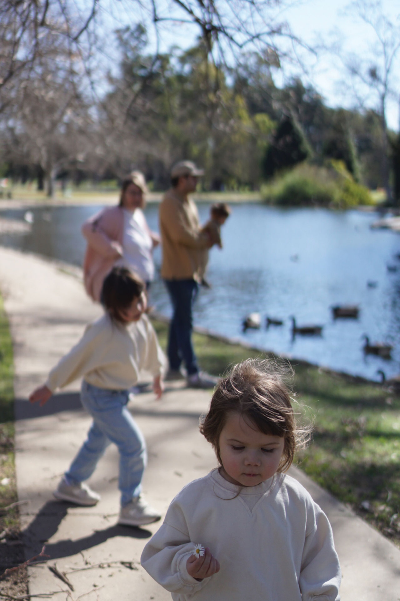 Photograph of Family at the Park Feeding Ducks at a Pond Before Preset