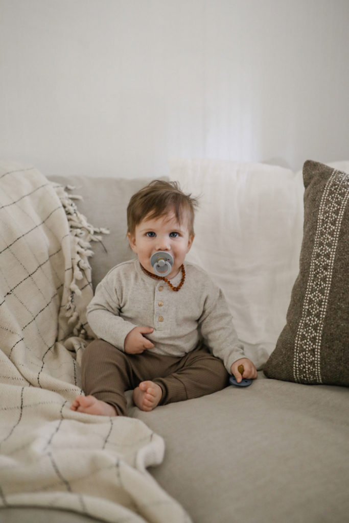 Infant with Pacifier Sitting on Large Sofa