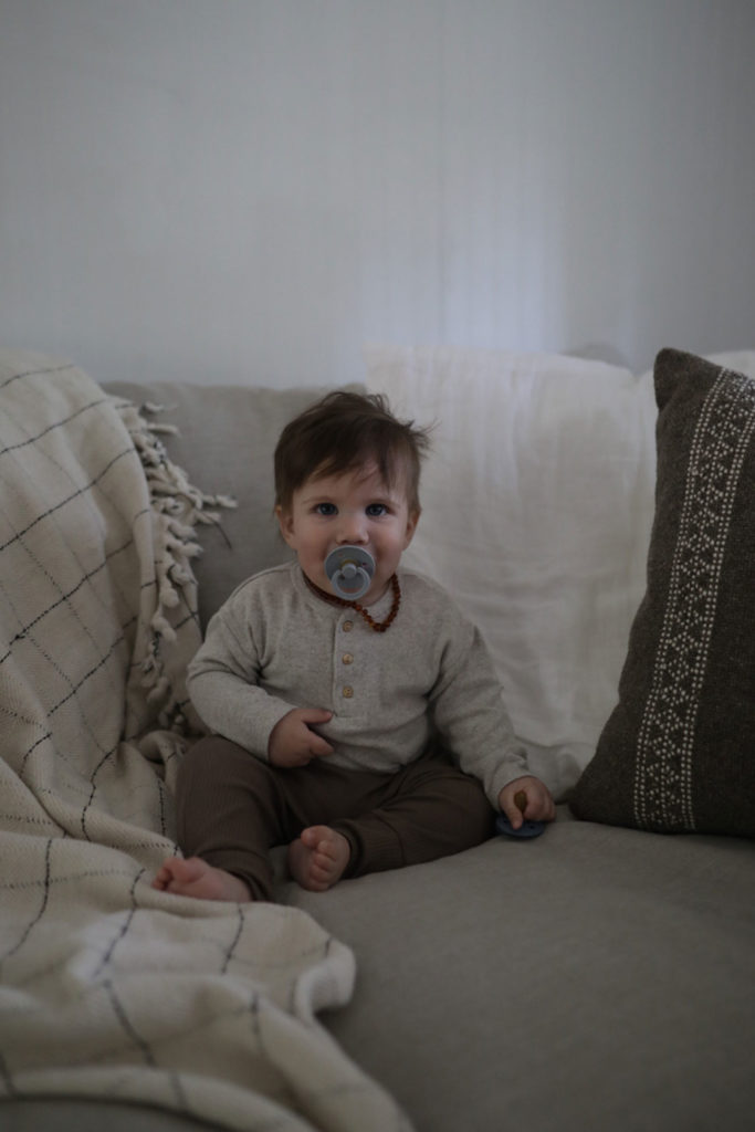 Infant with Pacifier Sitting on Large Sofa